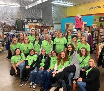 adults inside of a store wearing green essentia shirts 