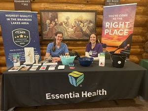 Two Essentia employees sitting and smiling behind a desk.