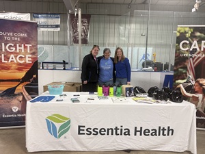 Three Essentia employees stand together while smiling behind a desk