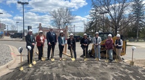 People wearing hard hats and holding shovels on a newly graded land
