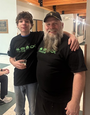 A young man puts his arm around an older man's shoulders while the man smiles.