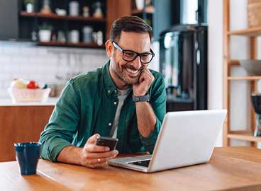A man with glasses smiling while on a video visit with computer.